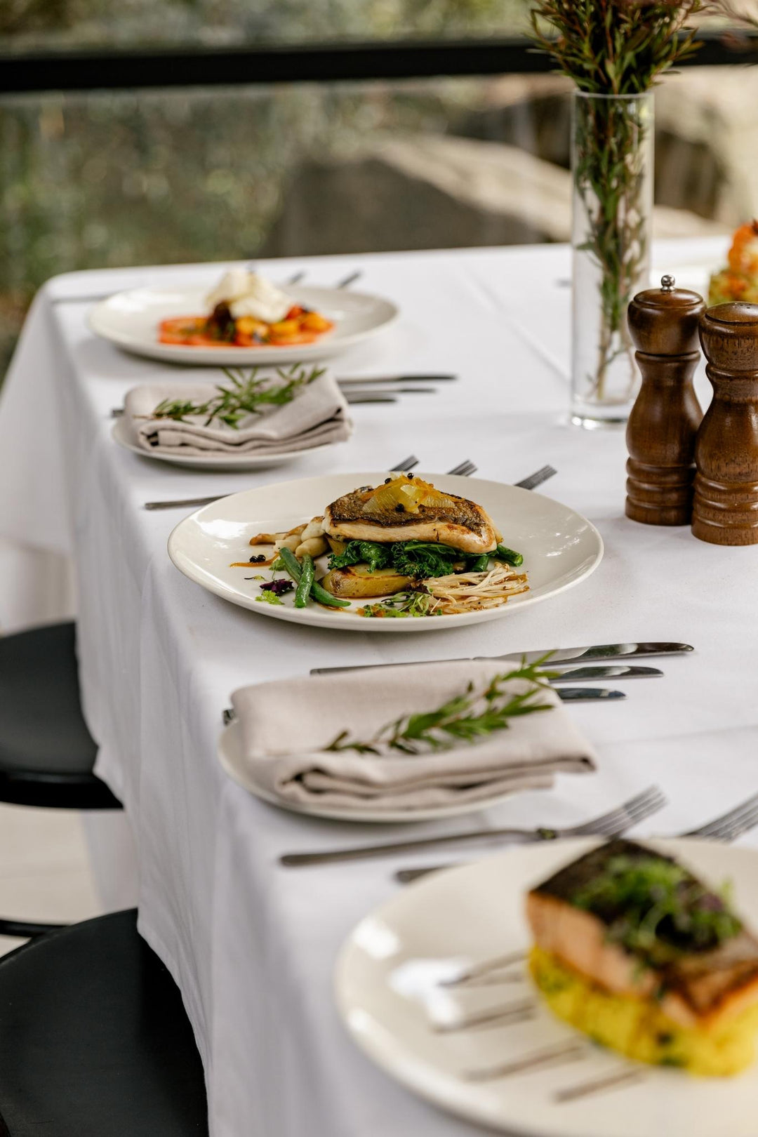 Elegant dining table set with plates of food, cutlery, and decorative elements.