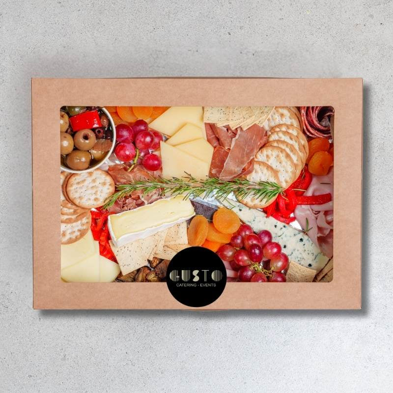 Gourmet food platter in a cardboard box with visible brand logo on a gray background
