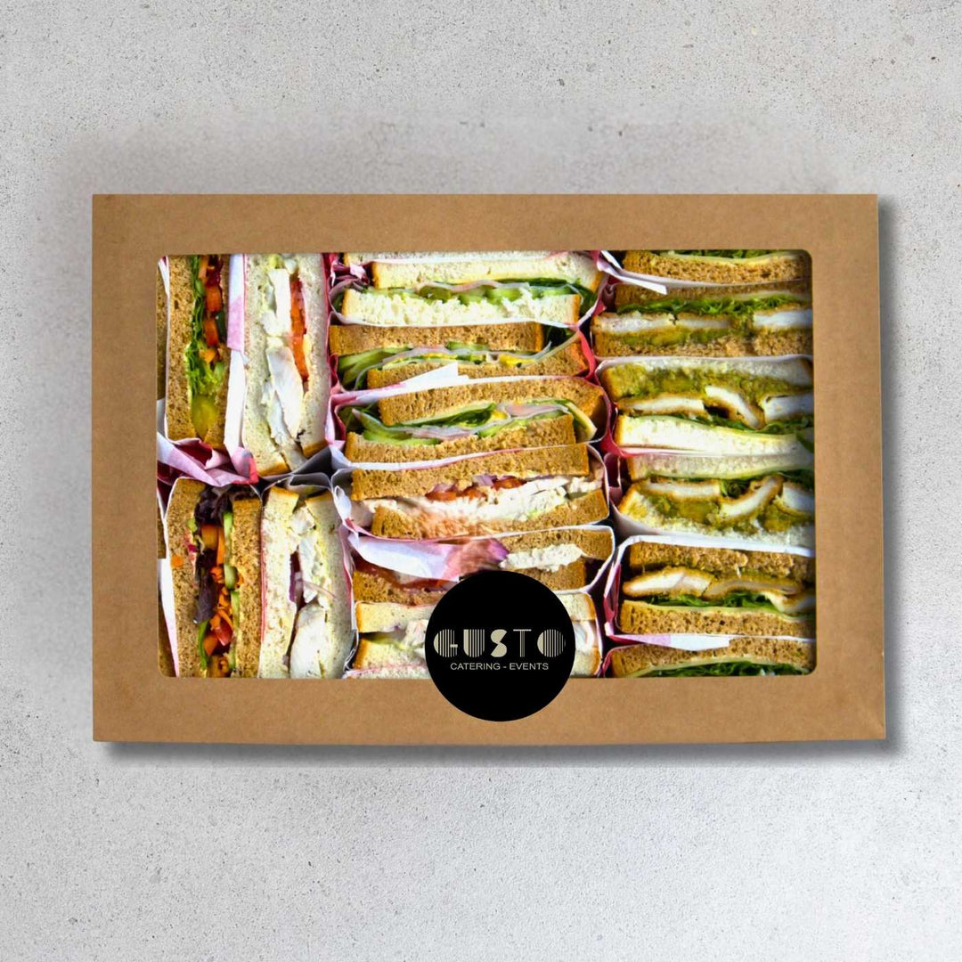 Box of assorted sandwiches with a visible brand logo on a gray background