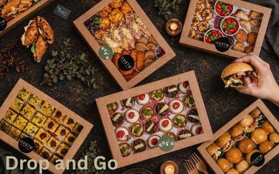 Assorted food boxes with a hand holding a burger on a dark surface, featuring the brand 'Drop and Go'.