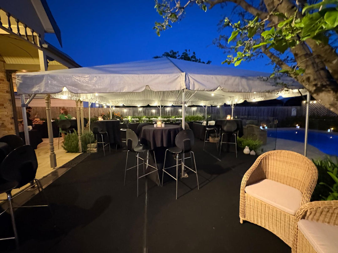 Outdoor event setup with white canopy, chairs, and tables under a clear blue sky.