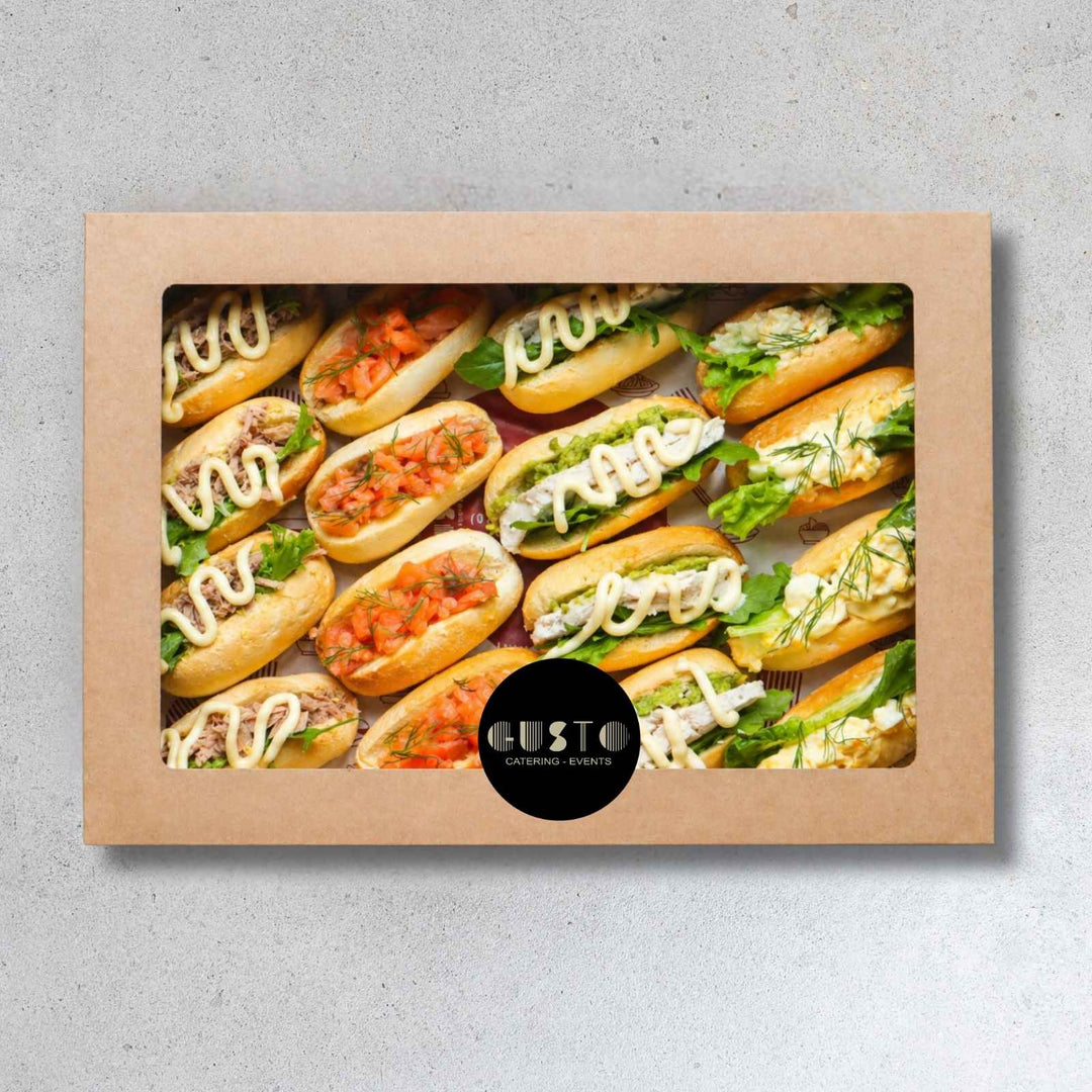 Box of Gusto Catering mini sandwiches on a gray background