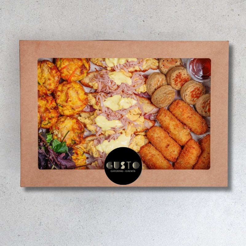 Assorted food items in a cardboard box with ' Gusto' logo.