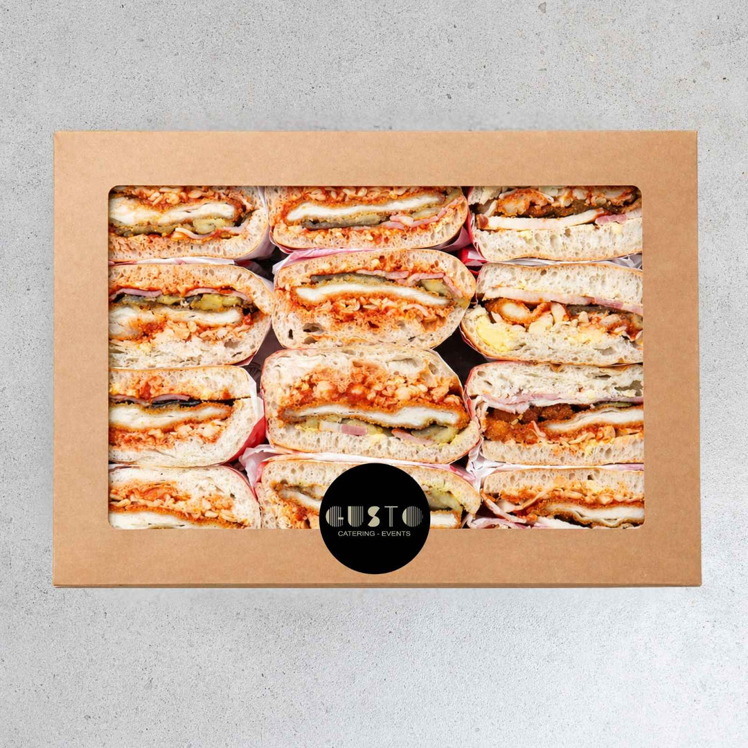 Box of assorted sandwiches with 'Gusto Catering Events' logo on a gray background