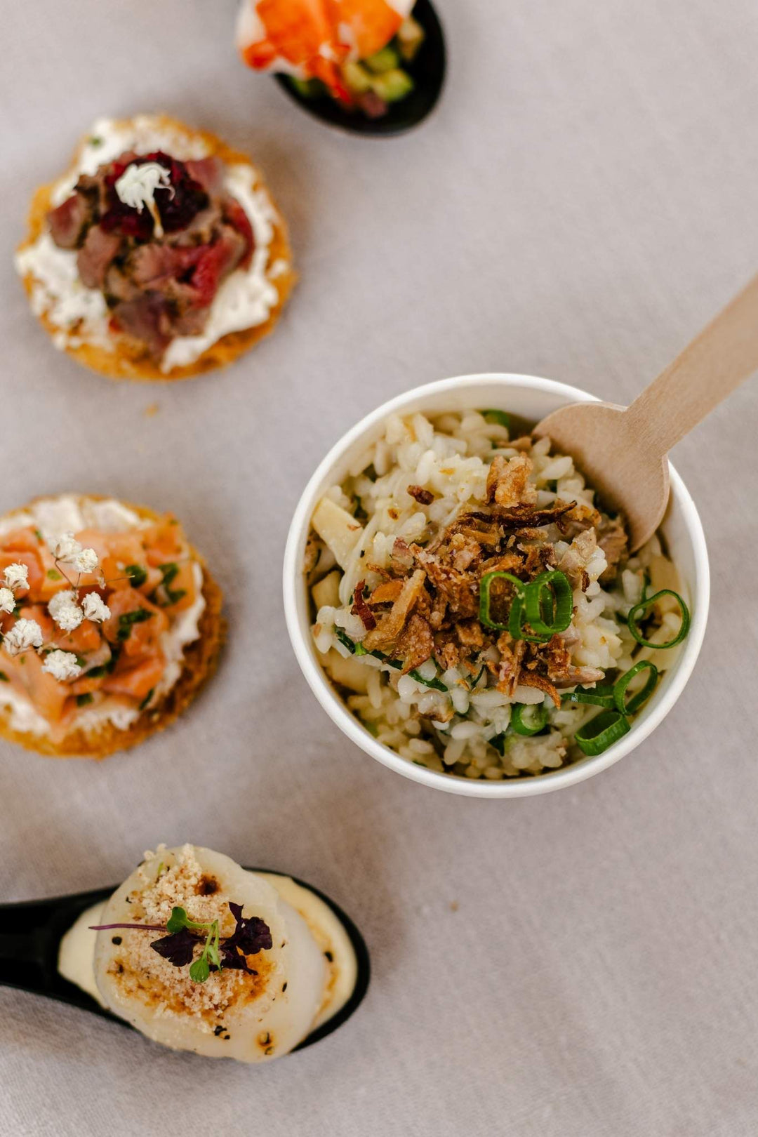 Bowl of pasta with toppings on a table with crackers and a small dish.